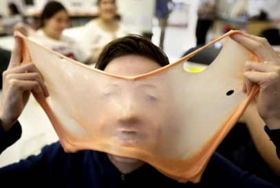  student holding slime stretched across his face