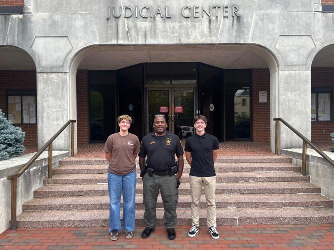  two student stand with Sheriff outside
