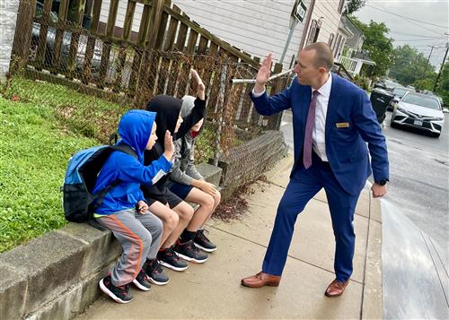 Superintendent high fives students waiting for the school bus